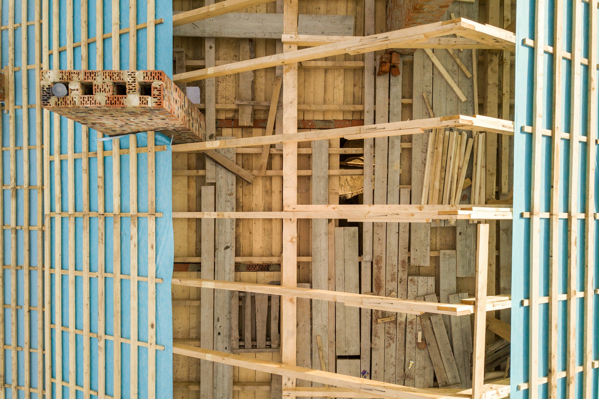 Aerial view of a brick house with wooden roof frame under construction