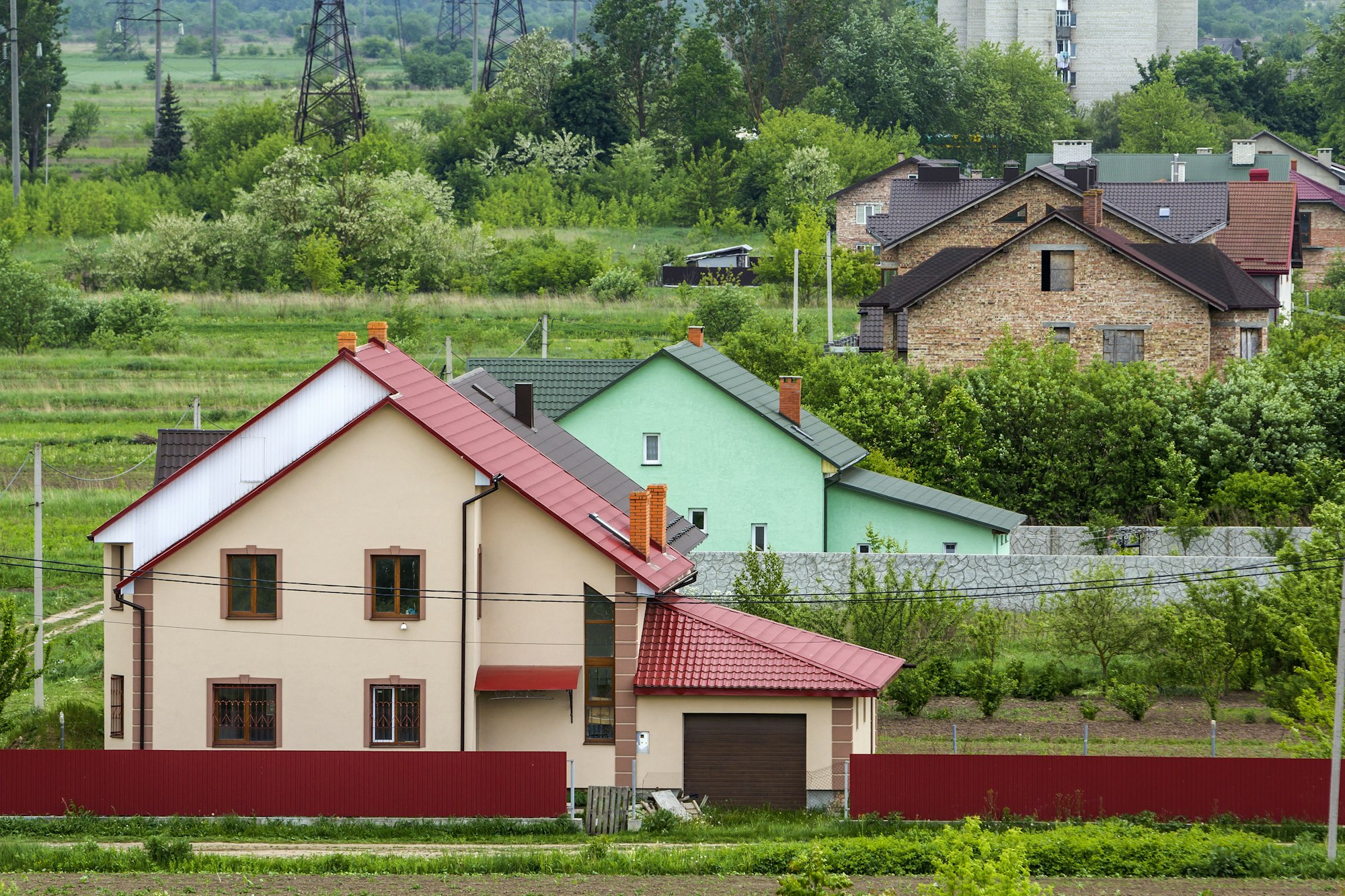 Close-up of big new comfortable two-storied new cottage with green tile roof, big yard, plastic